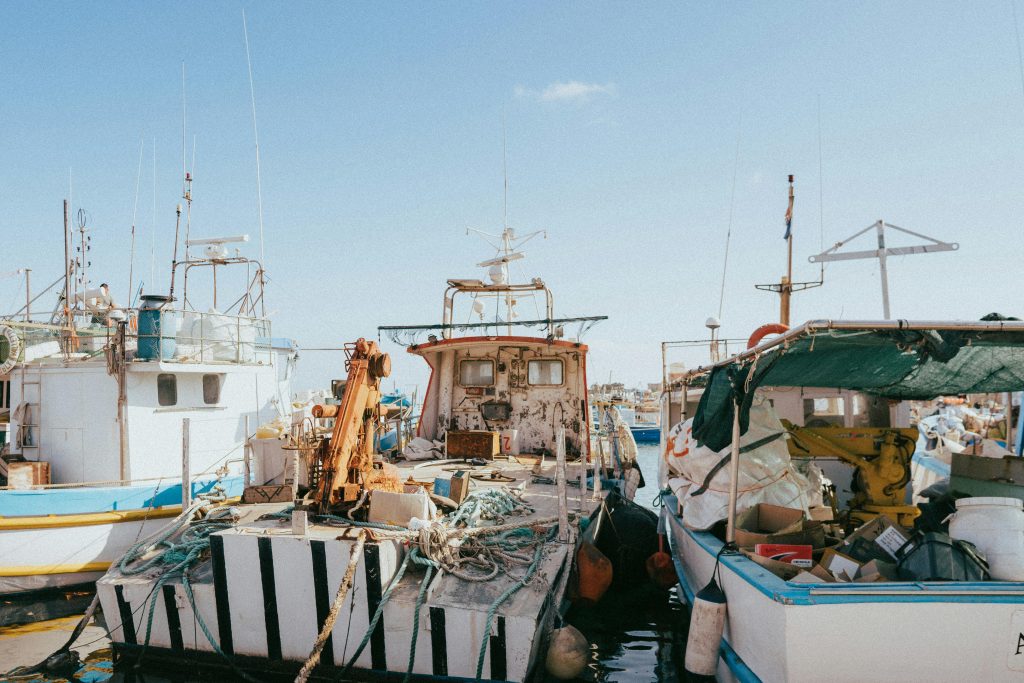 Fishing boats moored in Marsaxlokk harbor, Malta, under a clear blue sky. Vibrant and picturesque setting.